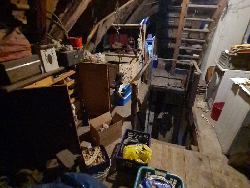 Vollgestellter Dachboden mit Möbeln und Kisten vor der Dachbodenentrümpelung